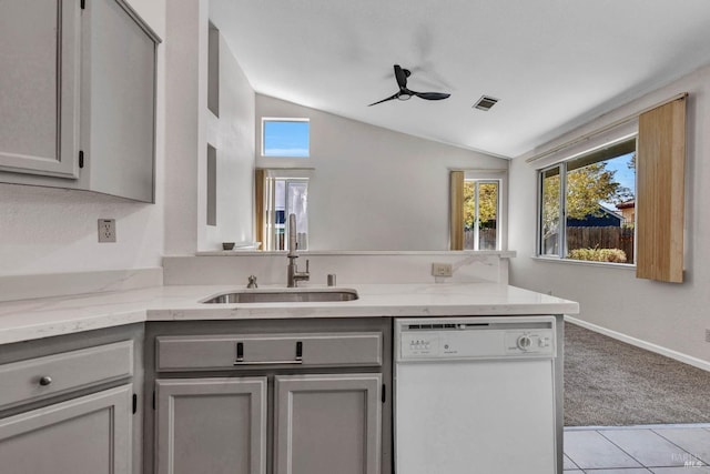 kitchen featuring lofted ceiling, sink, gray cabinets, dishwasher, and light stone countertops