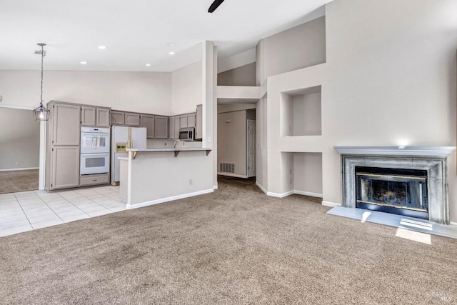 unfurnished living room featuring high vaulted ceiling, light colored carpet, and ceiling fan