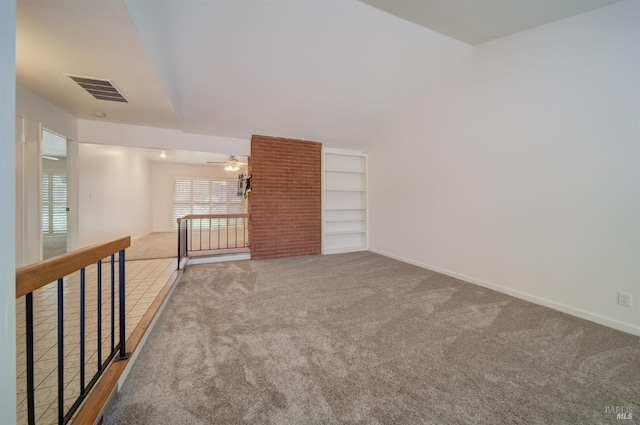 spare room featuring ceiling fan, built in features, vaulted ceiling, and carpet