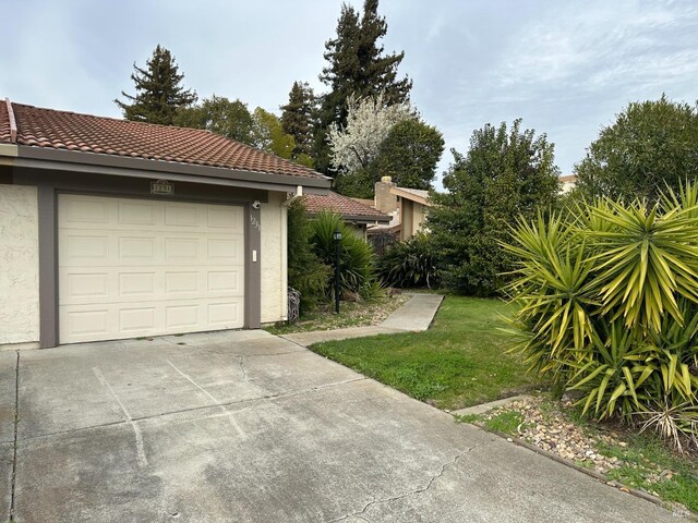 view of side of home featuring a garage and a lawn