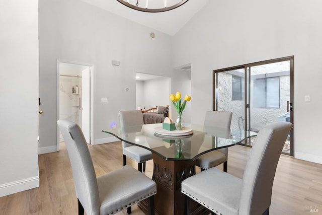 dining room featuring high vaulted ceiling and light wood-type flooring