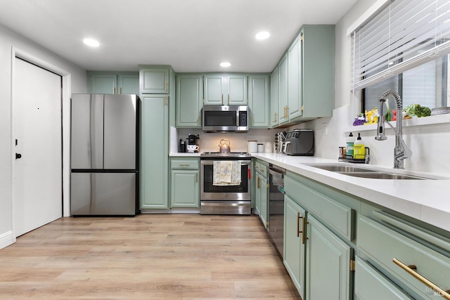 kitchen featuring sink, light hardwood / wood-style floors, green cabinetry, and appliances with stainless steel finishes