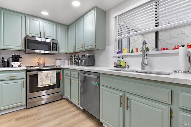 kitchen featuring sink, green cabinets, light hardwood / wood-style flooring, and appliances with stainless steel finishes