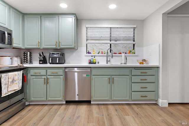 kitchen featuring appliances with stainless steel finishes, sink, and light wood-type flooring