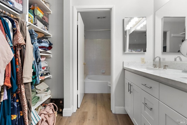 full bathroom with tiled shower / bath, wood-type flooring, toilet, and vanity