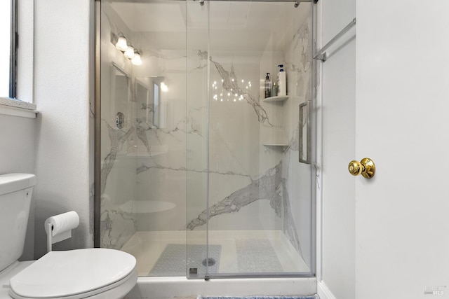 bathroom featuring toilet and a shower with shower door