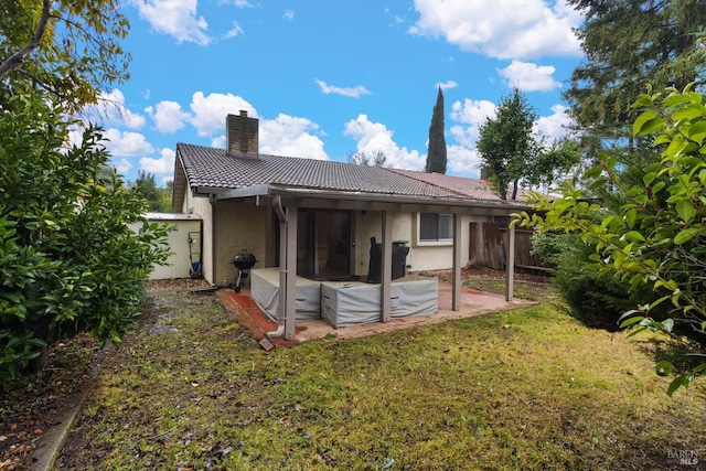 back of property with a patio area and a lawn