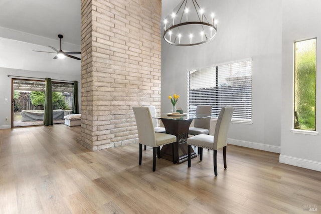 dining room featuring a towering ceiling, a wealth of natural light, and light hardwood / wood-style flooring