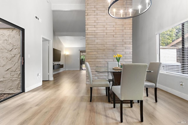 dining area with high vaulted ceiling, plenty of natural light, and light hardwood / wood-style floors