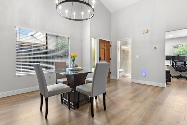 dining area with a high ceiling, an inviting chandelier, and light wood-type flooring