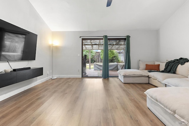 living room with ceiling fan, vaulted ceiling, and light wood-type flooring