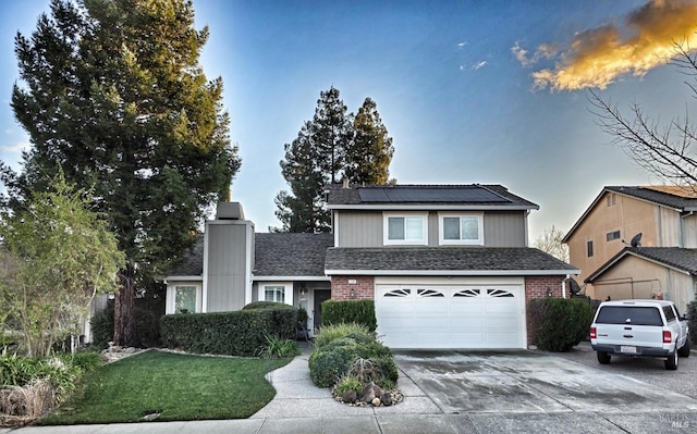 front of property featuring a garage, a yard, and solar panels