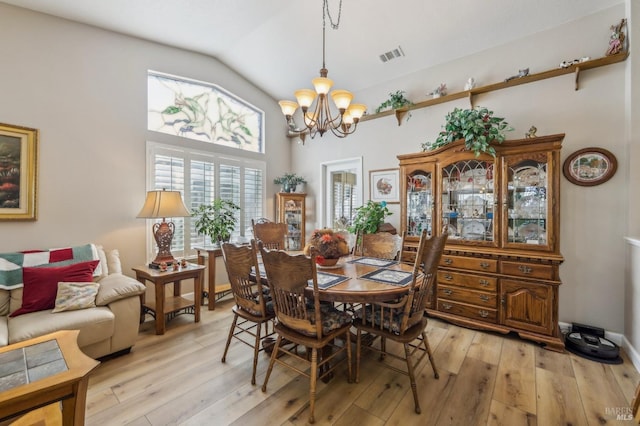 dining space featuring vaulted ceiling, a chandelier, and light hardwood / wood-style floors