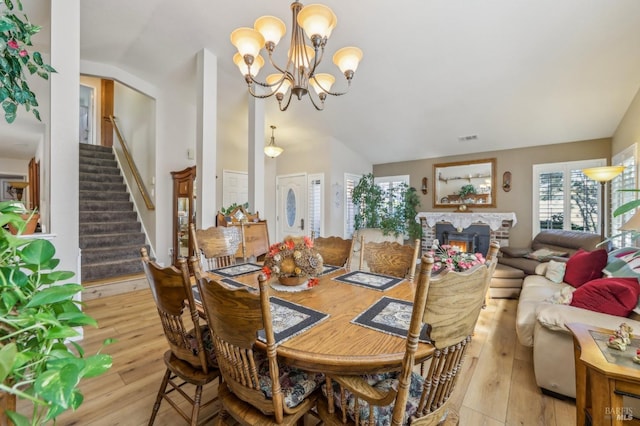 dining space with a notable chandelier, vaulted ceiling, and light wood-type flooring