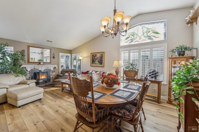 dining area with light hardwood / wood-style flooring, high vaulted ceiling, a chandelier, and a healthy amount of sunlight