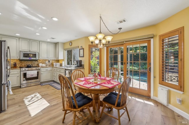 dining area with sink, an inviting chandelier, and light hardwood / wood-style flooring