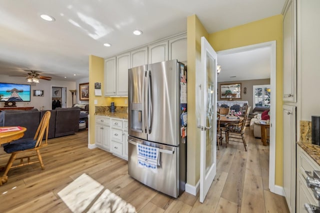 kitchen featuring stainless steel refrigerator with ice dispenser, white cabinetry, light stone counters, light hardwood / wood-style flooring, and ceiling fan