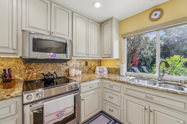 kitchen with stainless steel appliances, light stone countertops, sink, and decorative backsplash