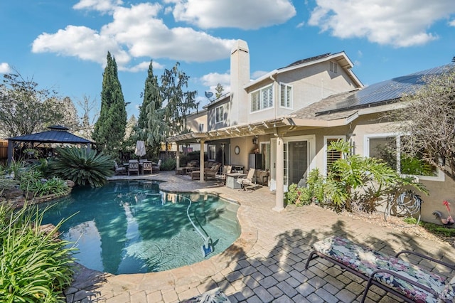 rear view of house with a fenced in pool, a gazebo, and a patio area