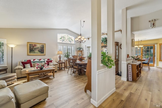 living room featuring vaulted ceiling, a notable chandelier, and light wood-type flooring