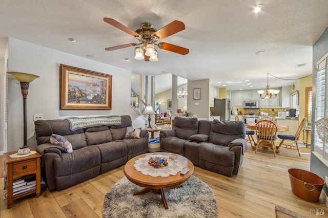 living room with ceiling fan with notable chandelier and light hardwood / wood-style flooring