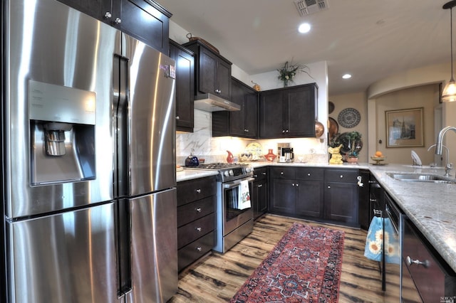 kitchen featuring sink, light hardwood / wood-style flooring, pendant lighting, stainless steel appliances, and light stone countertops