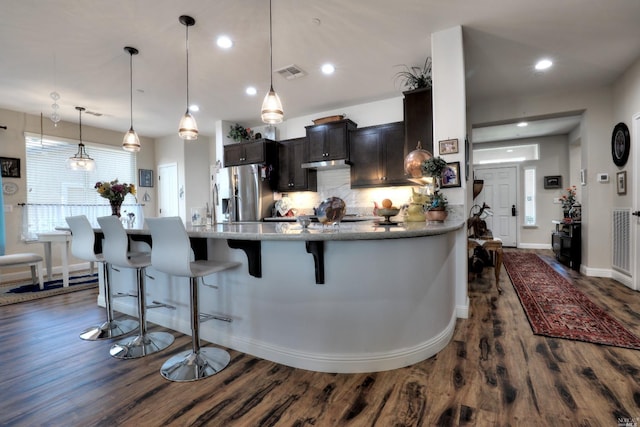 kitchen featuring pendant lighting, dark wood-type flooring, a breakfast bar area, backsplash, and stainless steel refrigerator with ice dispenser