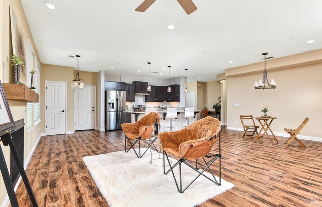 kitchen featuring light stone counters, tasteful backsplash, dark brown cabinetry, stainless steel fridge with ice dispenser, and decorative light fixtures