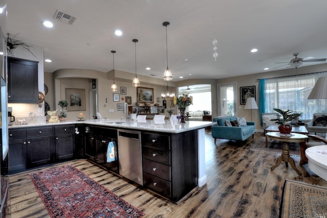 kitchen featuring pendant lighting, dishwasher, light stone countertops, and hardwood / wood-style flooring