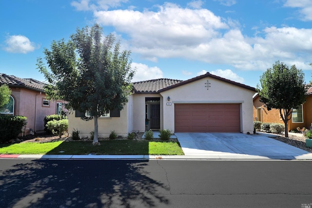 mediterranean / spanish house with a tile roof, an attached garage, driveway, and stucco siding