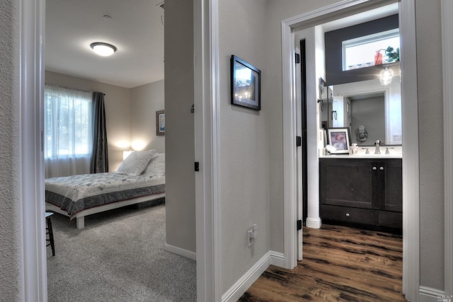 hallway featuring sink and dark carpet