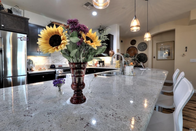 kitchen with stainless steel appliances, light stone countertops, and sink