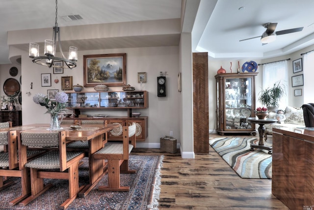 dining area featuring ceiling fan with notable chandelier and dark wood-type flooring