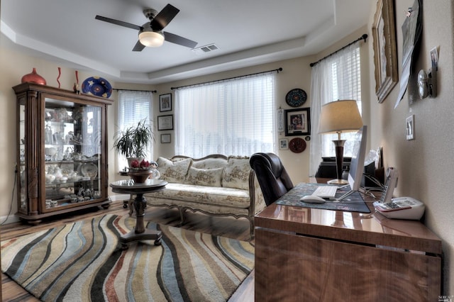 home office featuring ceiling fan, plenty of natural light, and a tray ceiling