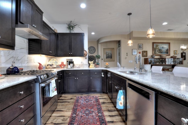 kitchen featuring appliances with stainless steel finishes, sink, decorative backsplash, hanging light fixtures, and light stone counters