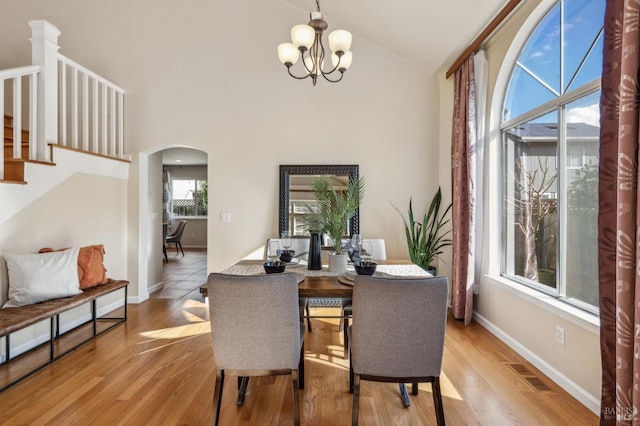 dining area featuring visible vents, arched walkways, an inviting chandelier, and wood finished floors