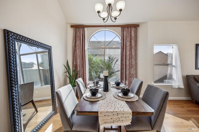 dining space featuring baseboards, light wood finished floors, and a chandelier