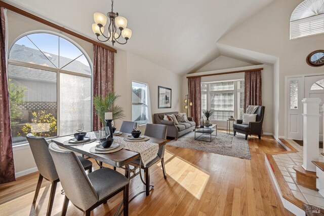 dining area with vaulted ceiling, light wood-style flooring, a notable chandelier, and baseboards