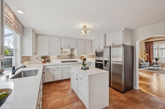 kitchen with light tile patterned floors, white cabinets, appliances with stainless steel finishes, and a sink