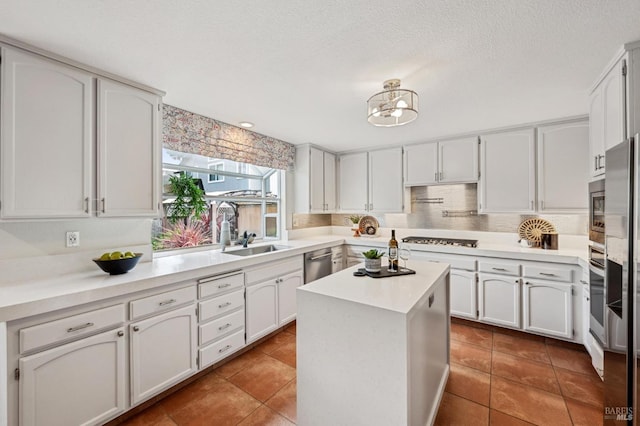 kitchen with light countertops, decorative backsplash, stainless steel appliances, white cabinetry, and a sink