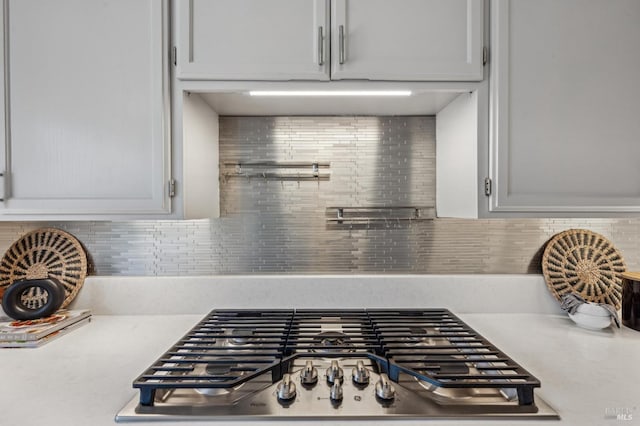 details with tasteful backsplash, stainless steel gas stovetop, and light countertops