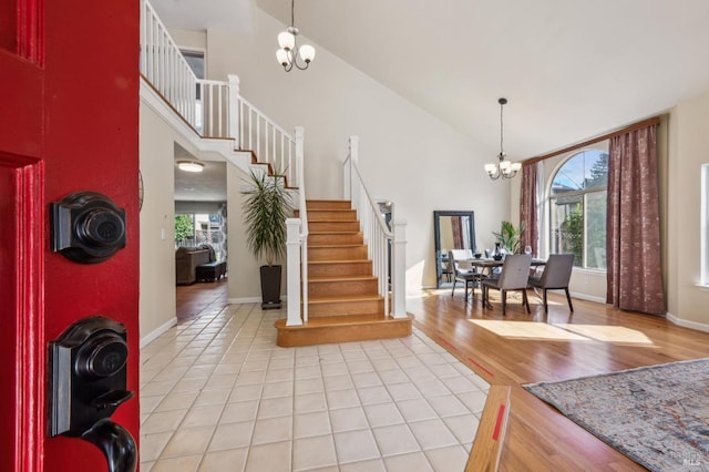 foyer with a healthy amount of sunlight, an inviting chandelier, stairs, and light wood finished floors