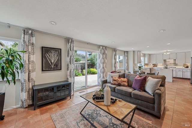 living area with light tile patterned floors, visible vents, a textured ceiling, and recessed lighting