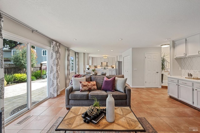 living area with light tile patterned floors, visible vents, and a textured ceiling