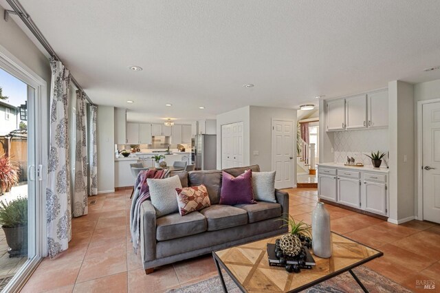 living room featuring light tile patterned flooring, stairway, plenty of natural light, and recessed lighting