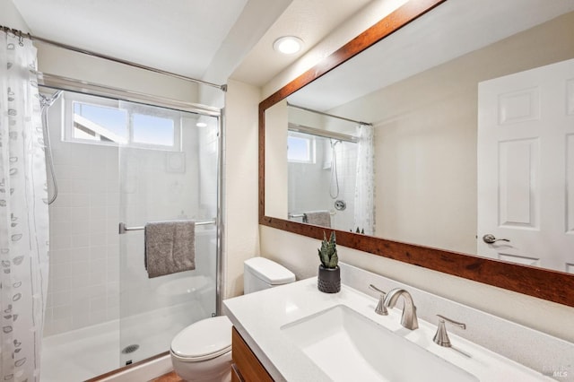 full bathroom featuring tiled shower, toilet, and vanity