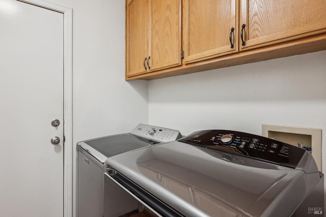 clothes washing area with cabinet space and washing machine and dryer