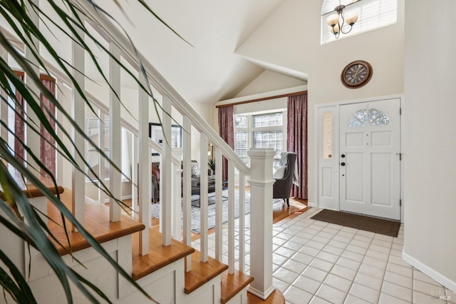 foyer entrance featuring baseboards, a chandelier, stairway, vaulted ceiling, and light tile patterned flooring