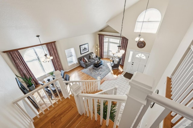 interior space with high vaulted ceiling, an inviting chandelier, and wood finished floors