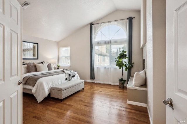 bedroom with visible vents, baseboards, lofted ceiling, and wood finished floors